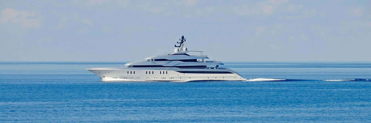 A large white yacht cruises through a calm, blue ocean under a clear sky. The sleek design of the vessel is accentuated by its streamlined profile.