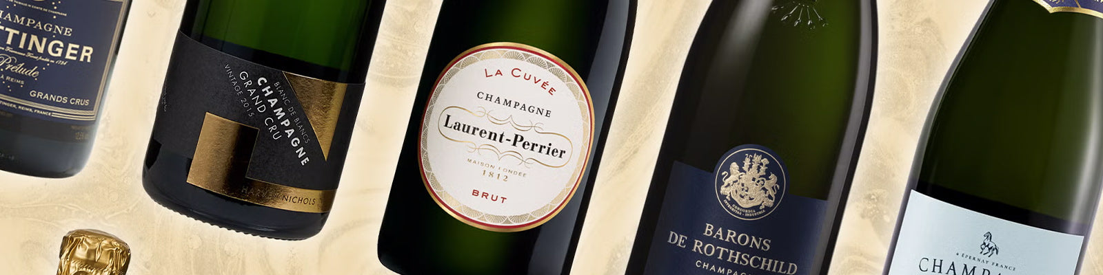 Assorted champagne bottles arranged on a light-colored background. Labels include Laurent-Perrier, Barons de Rothschild, and Taittinger. The bottles are slightly tilted and elegantly displayed.