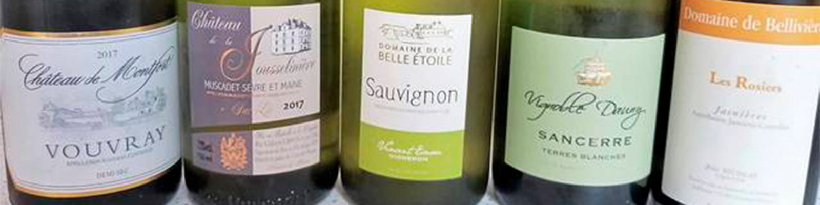 Una fila di cinque bottiglie di vino con diverse etichette, tra cui Vouvray, Muscadet, Sauvignon, Sancerre e Les Rosiers. Ogni bottiglia ha un marchio e un design distintivo.