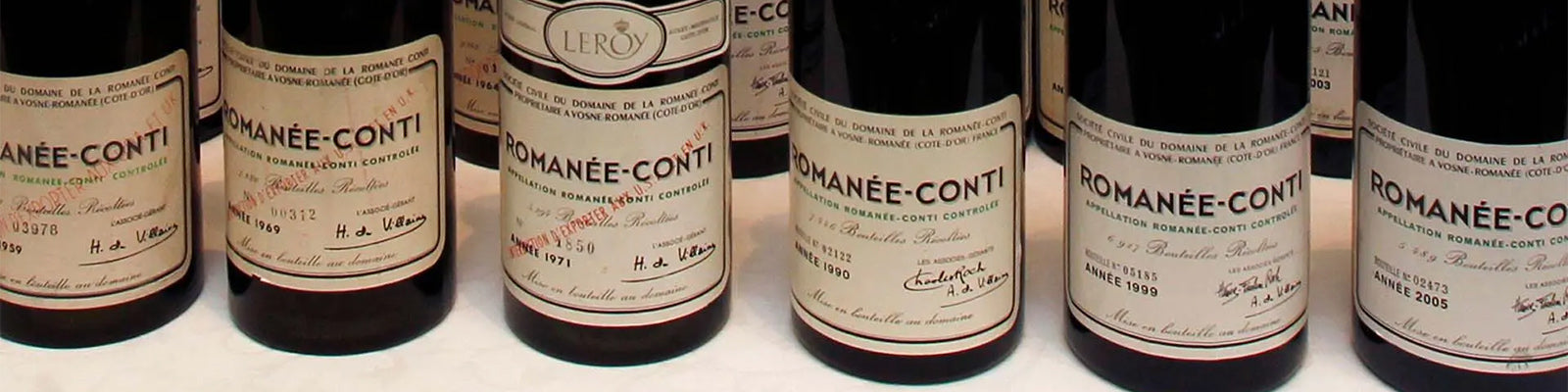 A row of Domaine de la Romanée-Conti wine bottles with vintage labels displayed, showcasing their prestigious Burgundy heritage. The labels contain detailed information about each bottle.