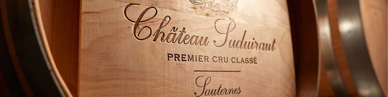 Close-up of a wooden wine barrel engraved with Château Suduiraut, Premier Cru Classé, Sauternes, highlighting the winery’s name and class.